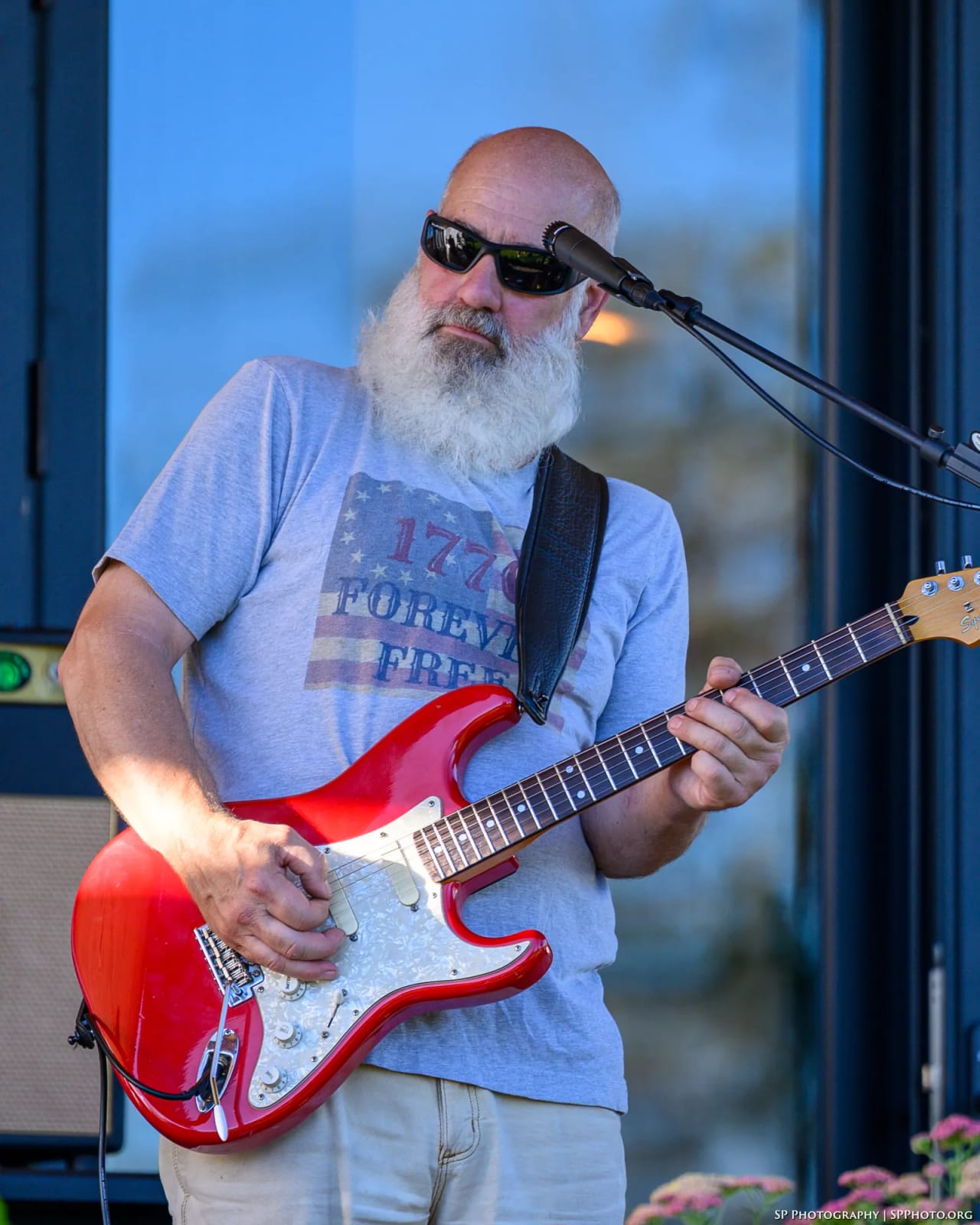 Carey Calhoun playing his red Stratocaster at dusk, his amp behind him