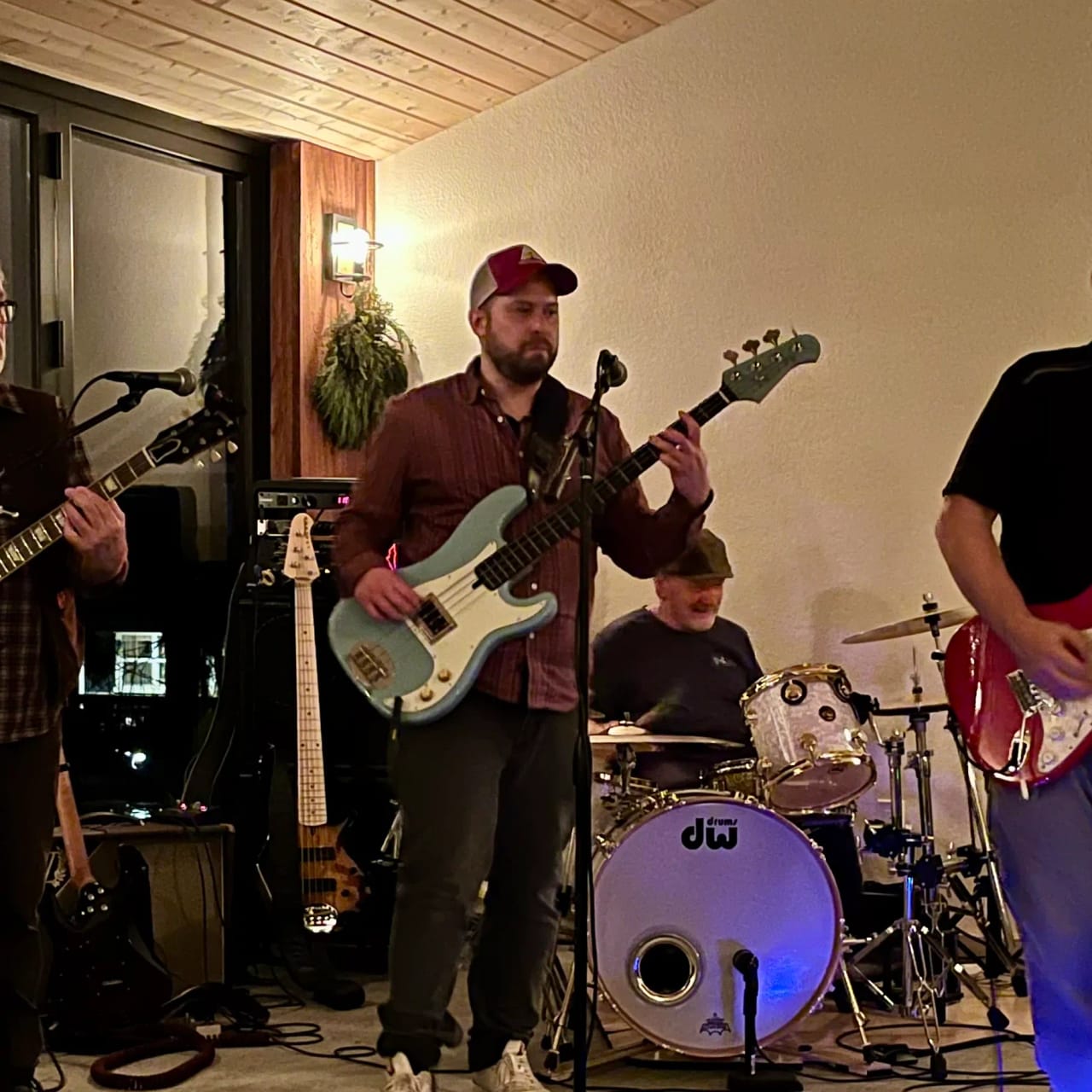 Grant Stampfli on his seafoam Precision bass at an indoor gig, the other players at the edges of the frame